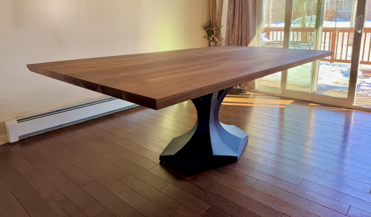 Custom walnut dining table with sculptural steel hourglass base handcrafted in Anchorage Alaska