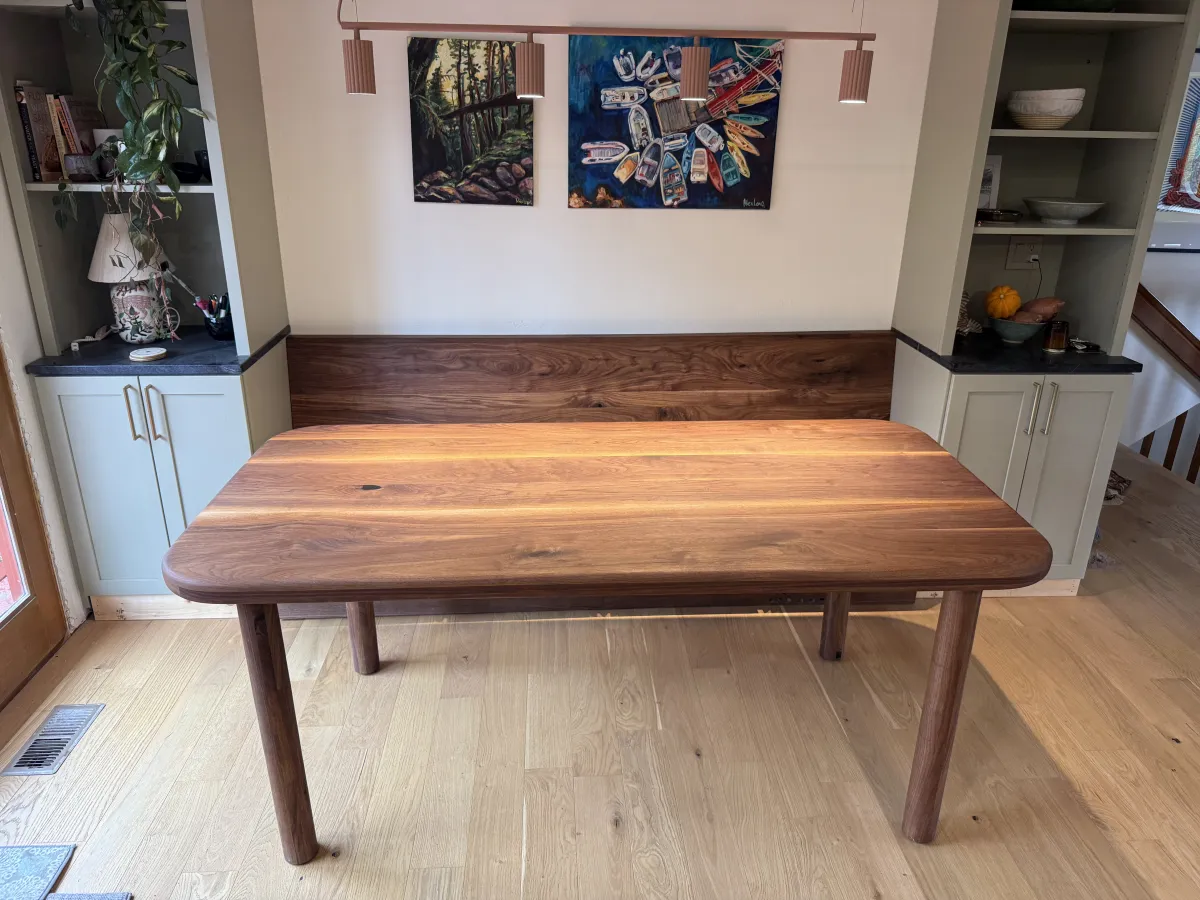 Walnut dining table with rounded edges in front of custom built-in cabinetry