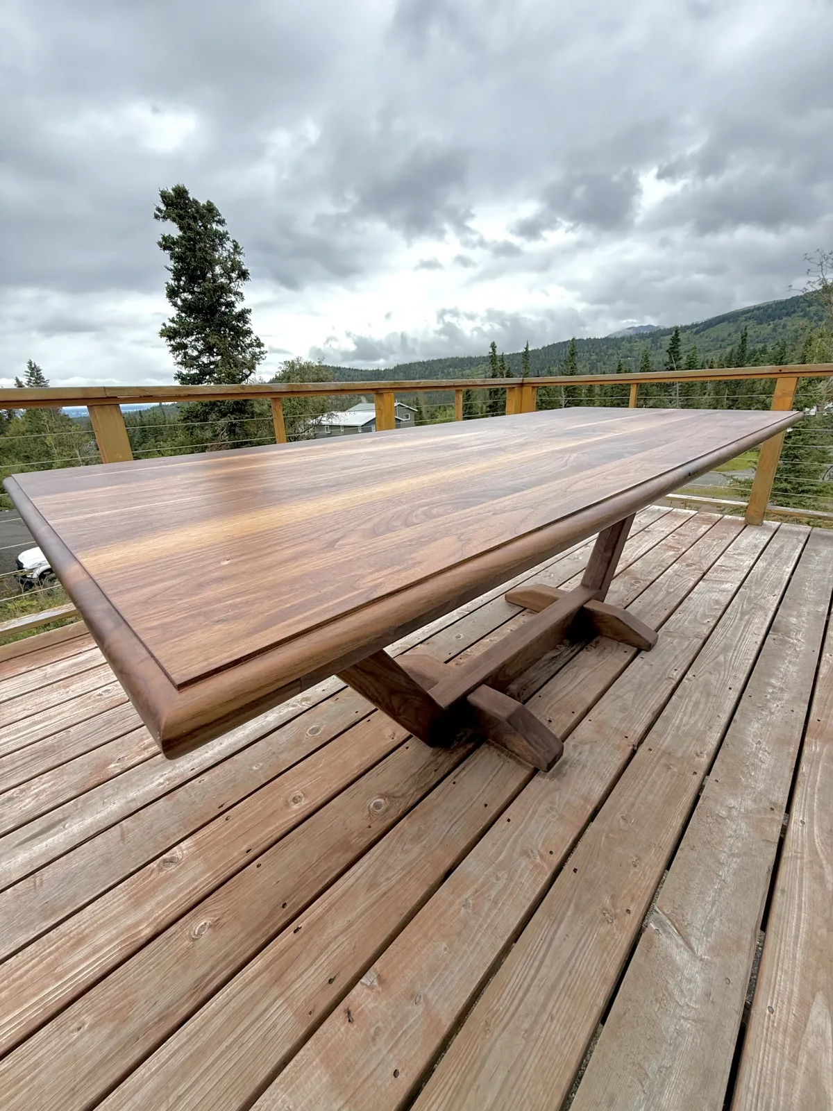 Walnut trestle dining table on deck with Alaska mountain backdrop