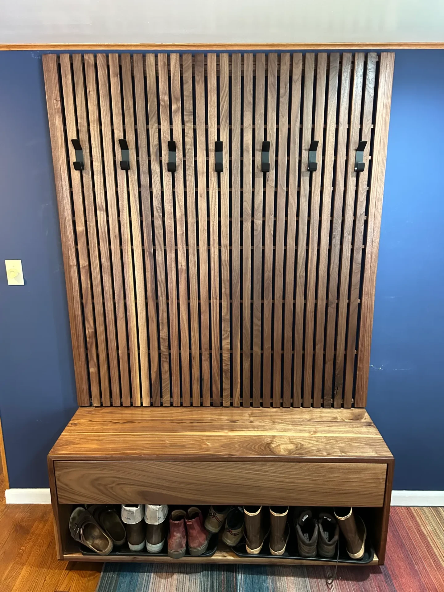 Tapia and Mark's walnut slat entryway organizer with coat hooks and storage